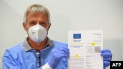 FILE - Doctor Christoph Borch holds a document as an example of a digital vaccination passport (CovPass) during a media event at the Babelsberg vaccination center in Potsdam near Berlin, northeastern Germany, on May 27, 2021.
