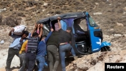 People push a tuk-tuk while crossing from Lebanon into Syria, as they flee the ongoing hostilities between Hezbollah and Israeli forces, at Masnaa border crossing, Lebanon.