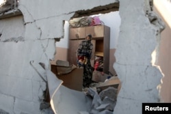 A Palestinian woman collects belongings as she inspects the damage to a house following an Israeli strike in Khan Younis in the southern Gaza Strip, Nov. 6, 2024.