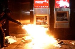 A protester feeds a flame near an ATM machine during an anti-government demonstration on New Year's Day to call for better governance and democratic reforms in Hong Kong, China, Jan. 1, 2020.