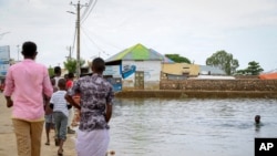 FILE - A child swims in the floodwaters as others walk past, in the town of Beledweyne, in central Somalia, Nov. 4, 2019.