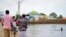 FILE - A child swims in the floodwaters as others walk past, in the town of Beledweyne, in central Somalia, Nov. 4, 2019.