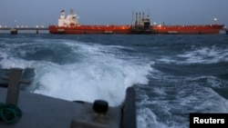 FILE - Oil gets pumped into a tanker docked at a PDVSA industrial complex in Venezuela's northeastern state of Anzoategui, April 15, 2015. Many foreign ports won’t accept tanks with oil-slicked hulls, and hand cleaning delays oil shipments vital to Venezuela’s economy. 