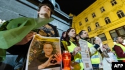 People hold portraits of the late Russian opposition leader Alexey Navalny, who died in a Russian Arctic prison, as they gather to pay tribute during a candle vigil in downtown Zagreb, Croatia, Feb. 23, 2024. Navalny's body reportedly was handed over to his mother on Feb. 24.