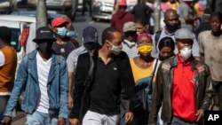 People wearing face masks to protect against coronavirus, walk on the street in downtown Johannesburg, South Africa, May 11, 2020. 