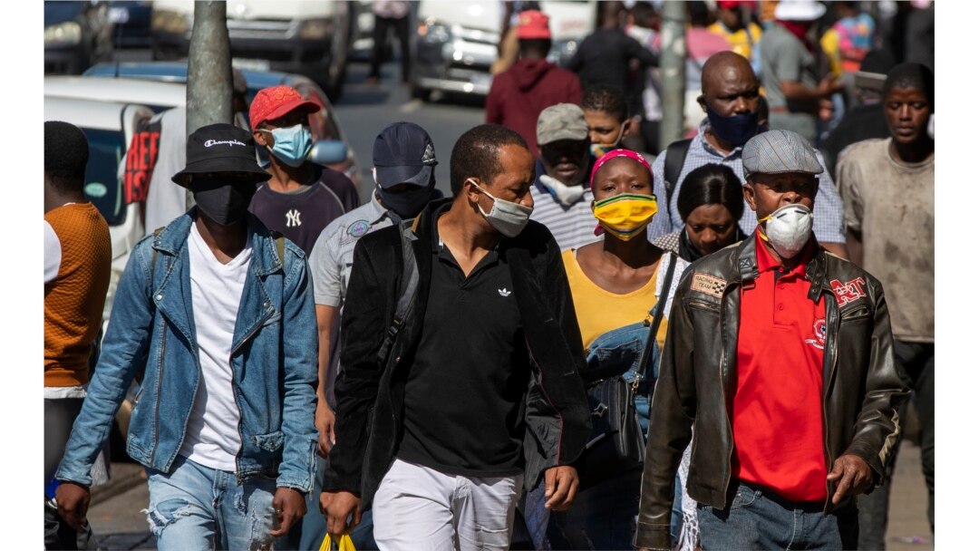 Para pejalan kaki memakai masker wajah untuk melindungi diri dari virus corona, di pusat kota Johannesburg, Afrika Selatan, 11 Mei 2020.