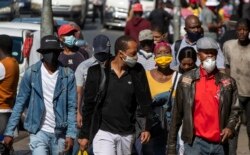 People wearing face masks to protect against coronavirus, walk on the street in downtown Johannesburg, South Africa, May 11, 2020.