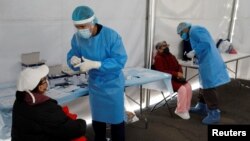 Trabajadores de la salud dan instrucciones antes de tomar una muestra del test para COVID-19, en Ciudad México, el 25 de noviembre de 2020.