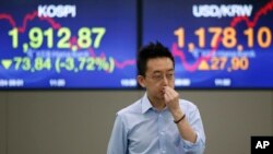 FILE - A currency trader walks by the screens showing the Korea Composite Stock Price Index (KOSPI), left, and the foreign exchange rate between U.S. Dollar and South Korean Won at the foreign exchange dealing room in Seoul, South Korea, June 24, 2016. 