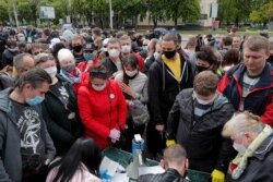 FILE - Supporters of Svetlana Tikhanovskaya collect signatures in support of her nomination as a candidate in the upcoming presidential election, in Minsk, Belarus, May 24, 2020.