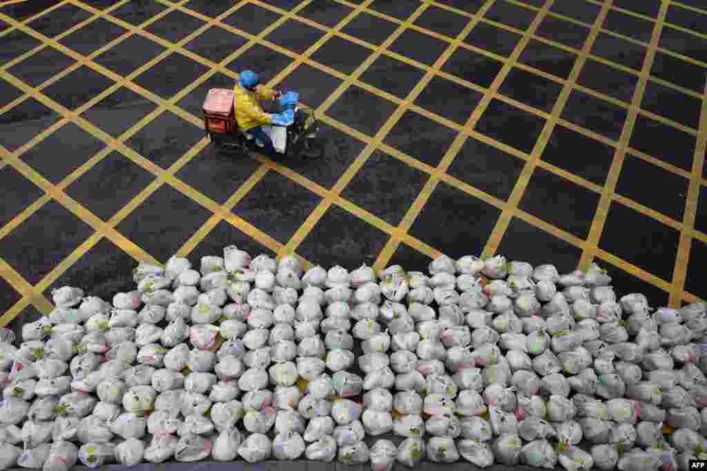 A man rides past bags of vegetables being prepared for delivery on an almost empty street in Wuhan, in China&#39;s central Hubei province.