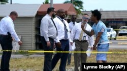 Clayton Dillard (kanan) berbicara dengan sejumlah penegak hukum untuk menanyakan kerabatnya di lokasi penembakan di sebuah gedung pertemuan di Miami, Minggu, 30 Mei 2021. (Foto: AP Photo/Lynne Sladky) 