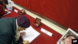 Residents sign a condolence book for Antoine De Leocour, in photo, and Vincent Delory in Linselles, northern France, Jan 10, 2011