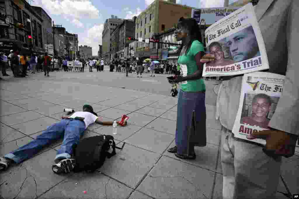 Un hombre lee un periódico mientras otro yace tirado en la calle en Newark.