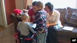 Josh Tolboe, 3, (left) was diagnosed with spina bifida and gets around in a red walker
