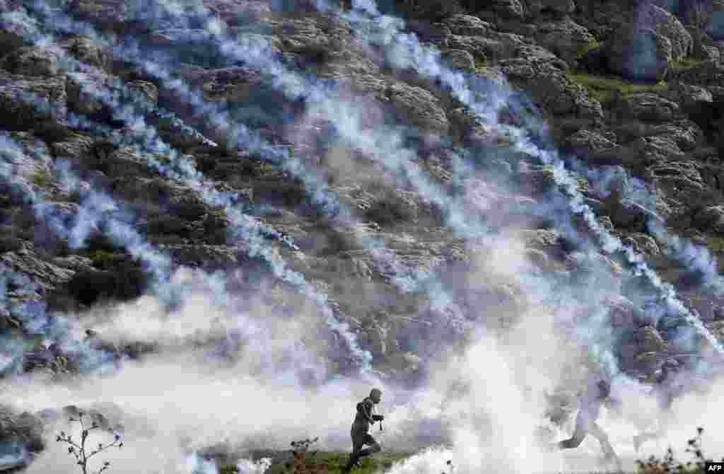 Palestinians run for cover from tear gas during clashes with Israeli soldiers in the village of Mugheer, about 25 kilometers northeast of the city of Ramallah, in the occupied West Bank.