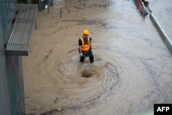 TOPSHOT - A worker works by a whirlpool as flood waters is drained on a road in Hong Kong on September 8, 2023.