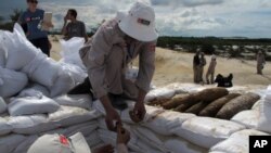 In this Wednesday, July 31, 2013 photo, a Vietnamese deminer hands unexploded ordinance to a colleague ahead of a controlled detonation in Vinh Thai, Vietnam. Aug. 15 marks the 40th anniversary of the end of American bombing operations in Indochina…