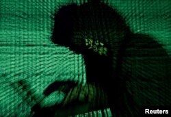 FILE- Man holds laptop computer as cyber code is projected on him in this illustration picture
