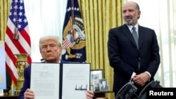 FILE - President Donald Trump holds an executive order about tariffs increase, flanked by U.S. Commerce Secretary Howard Lutnick, in the Oval Office of the White House in Washington, Feb. 13, 2025. 