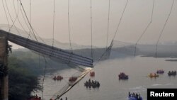 Sejumlah tim evakuasi tengah berupaya mencari korban yang jatuh ke dalam sungai akibat jembatan yang ambruk di Morbi, provinsi Gujarat, India, pada 31 Oktober 2022. (Foto: Reuters/Stringer)