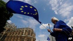 Seorang penentang Brexit mengibarkan bendera Uni Eropa dalam aksi unjuk rasa di depan parlemen Inggris, London (13/6). 