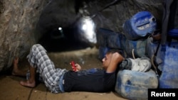 A Palestinian tunnel worker uses his mobile as he rests inside a smuggling tunnel beneath the Gaza-Egypt border in the southern Gaza Strip, July 19, 2013. 