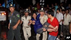 پـۆلیسێـک به‌ هاوکاری هاوڵاتیـیه‌ک که‌سێـکی بریندار هه‌ڵده‌گرنه‌وه‌، پـنوم بنه‌ی پایته‌ختی که‌مبۆدیا، شه‌وی دووشه‌ممه‌ 22 ی یازده‌ی 2010