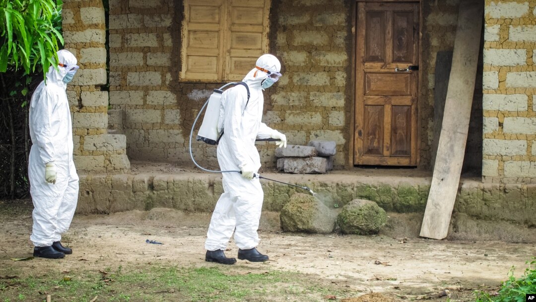 A healthcare worker in protective gear sprays disinfectant around the house of a person suspected to have Ebola virus in Port Loko Community, situated on the outskirts of Freetown, Sierra Leone, Oct. 21, 2014. 