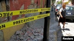 FILE - A resident evades rubble after an earthquake, in Oaxaca, March 20, 2012.