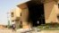 A man passes a bank building burnt during protests over cooking oil and fuel subsidy cuts in Khartoum September 26, 2013.