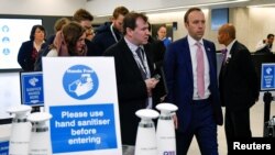 FILE - Britain's Health Secretary Matt Hancock (R) walks past a hand washing station as he leaves after talking about the coronavirus at the annual conference of the British Chambers of Commerce in London, March 5, 2020.