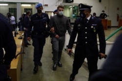 Gabriel Natale-Hjorth, center, is escorted by police officers during the trial for the slaying of an Italian plainclothes police officer, in Rome, May 5, 2021.