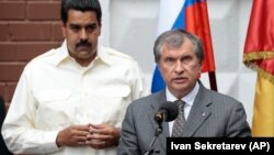 FILE - Venezuela's President Nicolas Maduro, left, listens as CEO of state-controlled Russian oil company Rosneft Igor Sechin speaks during a ceremony for naming a street after late Venezuelan President Hugo Chavez in Moscow, Russia, on Tuesday, July 2, 2013.