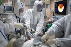 FILE - Doctors perform a tracheal intubation on a coronavirus patient for artificial lung respiration at an intensive care unit of the Filatov City Clinical Hospital in Moscow, Russia, May 15, 2020.