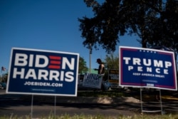 Biden and Trump campaign signs are displayed as voters line-up to cast their ballots during early voting at the Alafaya Branch Library in Orlando, Florida, on Oct. 30, 2020.