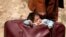 Seorang anak tertidur lelap di sebuah tas di desa Beit Sawa, sementara keluarganya berusaha mengungsi dari Ghouta Timur, Suriah.