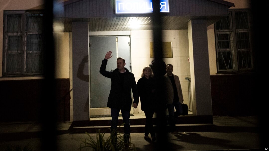 Pemimpin oposisi dan kandidat presiden Rusia, Alexei Navalny (kiri) melambai kepada pendukungnya setelah keluar dari kantor polisi di Moskow hari Jumat (29/9).