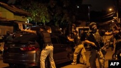 FILE - Philippine Drug Enforcement Agency (PDEA) agents and police secure a part of a street as they search a house looking for a suspected drug dealer during a raid in Maharlika Village, Taguig, south of Manila, Feb. 28, 2018. 