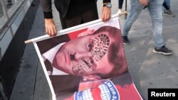 Demonstrators hold banners during a protest against France, in Istanbul,Turkey, Oct. 27, 2020. 