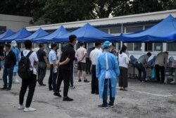 FILE - People who had their cars' license plates recorded near Xinfadi market, a new coronavirus cluster, wait in line for swab tests for the coronavirus, at a testing center in Beijing, China, June 17, 2020.