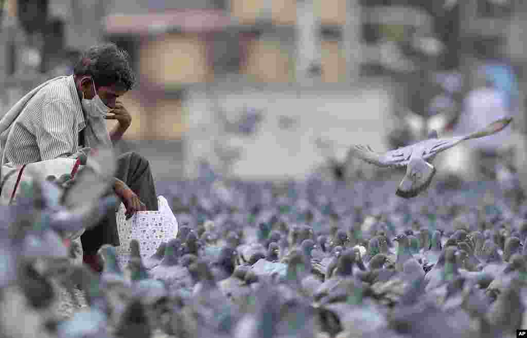 A man wearing a face mask is surrounded by pigeons during a lockdown aimed at preventing the spread of new coronavirus in Hyderabad, India.