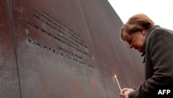German Chancellor Angela Merkel places a candle at the Berlin Wall Memorial during the central commemoration ceremony for the 30th anniversary of the fall of the Berlin Wall, on Nov. 9, 2019 at the Berlin Wall Memorial at Bernauer Strasse in Berlin.
