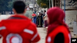 Des membres de la Croix-Rouge syrienne près des véhicules de secours dans la ville assiégée de Madaya à environ 24 kilomètres de Damas, en Syrie, le 11 janvier 2016. (AP Photo)