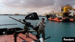 A rebel holds the Cyrenaica flag while standing on a boat where a North Korean-flagged tanker had loaded crude oil, at Es Sider port in Ras Lanuf, Libya, March 11, 2014.