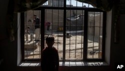 A boy stands at window as an official from the World Food Program interviews his family, in Kabul, Afghanistan, Nov. 18, 2021. 