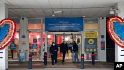People leave the Charing Cross hospital in London, Jan. 8, 2021, as Britain’s National Health Service will now employ a little-used field hospital specially built at a huge exhibition center in east London in the early days of the coronavirus pandemic las