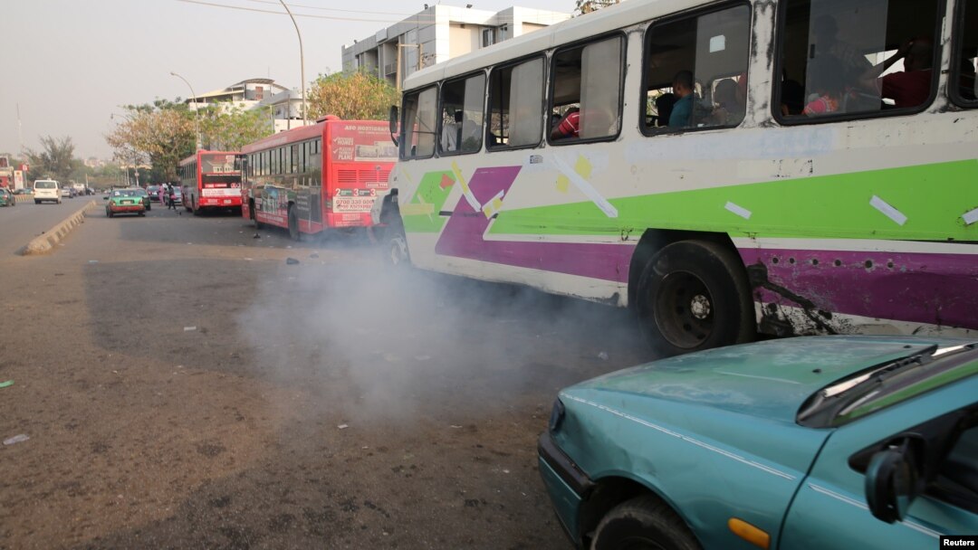 FILE - A bus leaves as smoke is seen at a bus park in Abuja, Nigeria, February 1, 2017. 