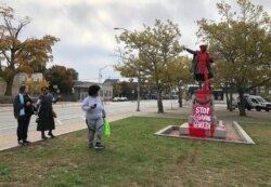 People stop to view red paint covering a statue of Christopher Columbus on Monday, Oct. 14, 2019, in Providence, R.I., after it was vandalized on the day named to honor him as one of the first Europeans to reach the New World.