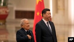 Salvadoran President Salvador Sanchez Ceren (L) standing next to Chinese President Xi Jinping, places his hand on his chest as the national anthem of El Salvador is played during a welcome ceremony held at the Great Hall of the People in Beijing, Nov. 1, 2018.